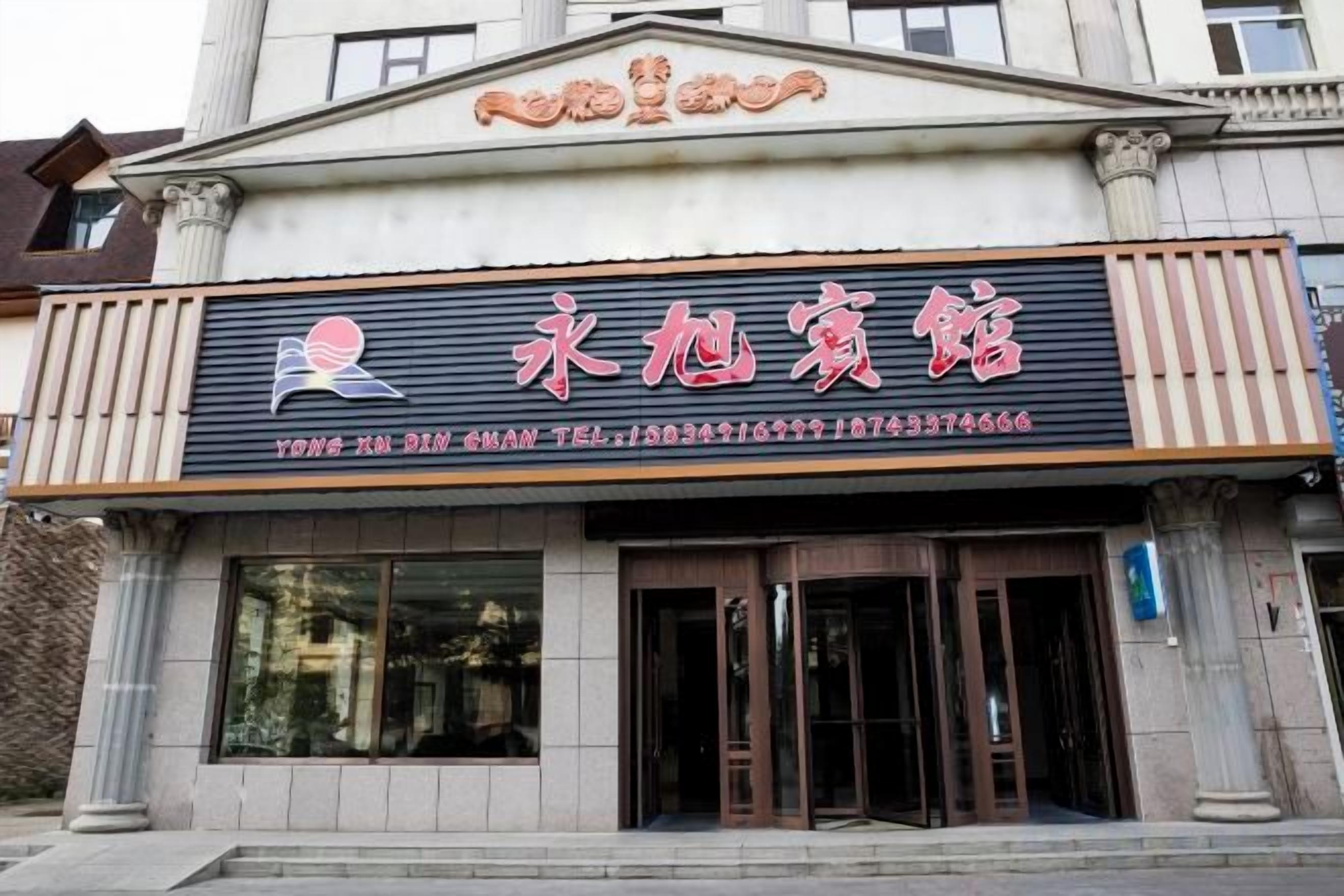 A building with a sign that reads '永恒宾馆' and a telephone number.