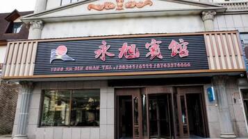 A building with a sign that reads '永恒宾馆' and a telephone number.