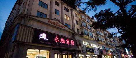 A multi-story building with illuminated signage for a hotel and other businesses.