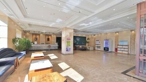 Un'ampia hall con una reception, una zona salotto e una pianta grande.