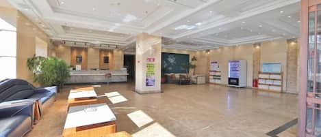 A spacious lobby with a reception desk, seating area, and a large plant.