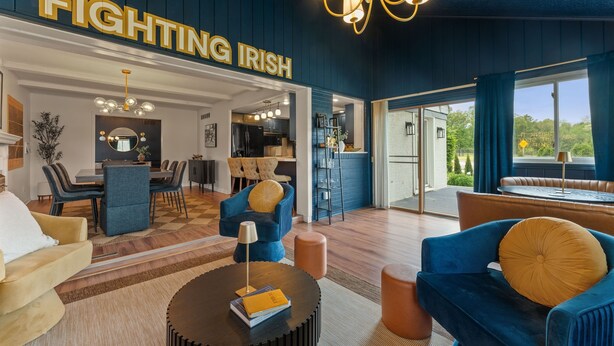 Ett rymligt vardagsrum med en stor skylt där det står ”FIGHTING IRISH”, ett matområde och ett kök som syns genom en öppen dörr.