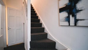 A staircase with dark carpeted steps leading to a white door.