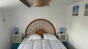 Un lit bien fait, avec une tête de lit en bois, deux tables de chevet avec des lampes et un mur orné de deux tableaux encadrés.