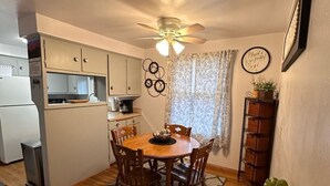 A compact kitchen with a dining area, a ceiling fan, and a clock on the wall. - Charming 2-bedroom house in peaceful De Pere with WiFi. Outdoor fire pit. (De Pere)