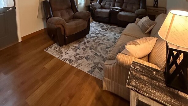 A living room with a brown leather sofa, two recliners, a patterned rug, and a lamp. - Charming 2-bedroom house in peaceful De Pere with WiFi. Outdoor fire pit. (De Pere)