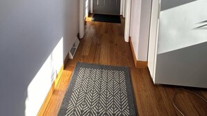 A narrow hallway with a wooden floor, a black and white rug, a refrigerator, and a door with a window. - Charming 2-bedroom house in peaceful De Pere with WiFi. Outdoor fire pit. (De Pere)