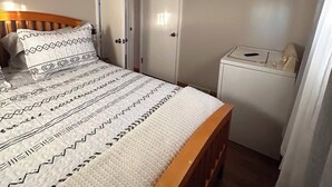 A bedroom with a bed, a wardrobe, a small table, and a TV mounted on the wall. - Charming 2-bedroom house in peaceful De Pere with WiFi. Outdoor fire pit. (De Pere)