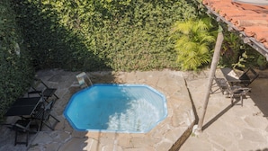 An octagonal swimming pool with a stone patio, surrounded by lush greenery and a tiled roof structure. - Comfort Suite 102 - Acayaca Inn (Centro Diamantina)