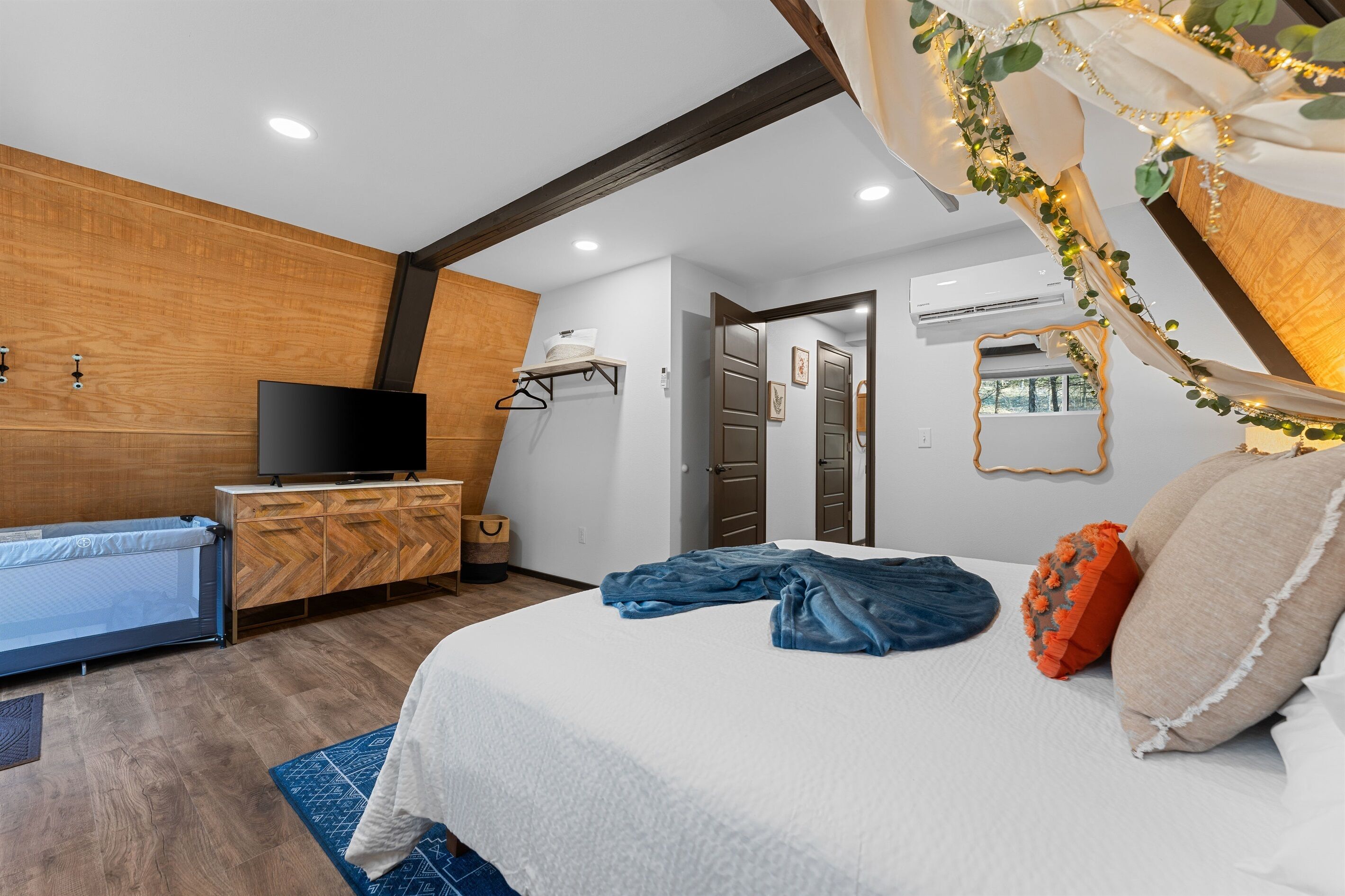 A modern bedroom with a bed, a TV, a wooden cabinet, and a hanging clothes rack.