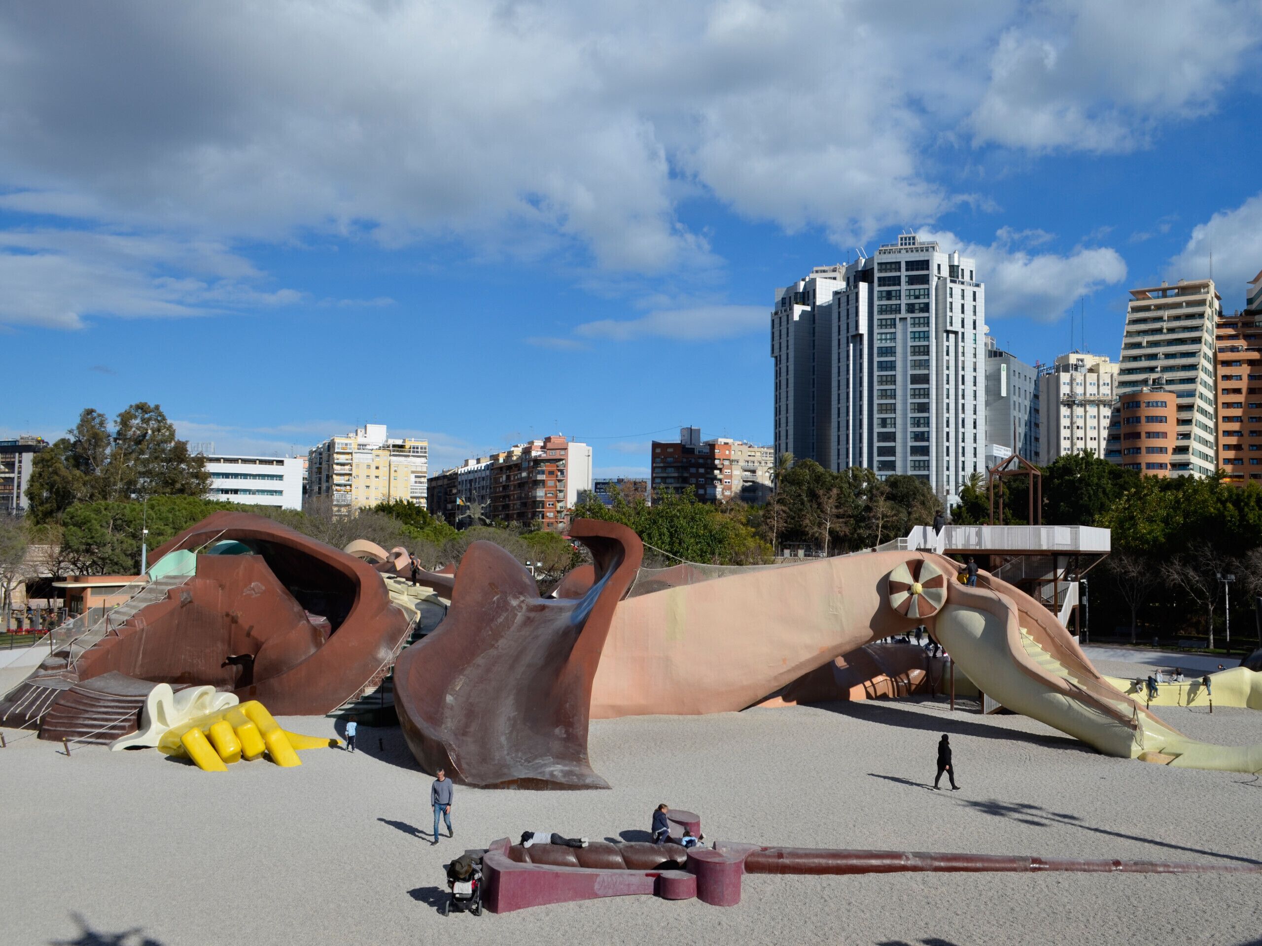 A large sculpture in an open area with a cityscape in the background.