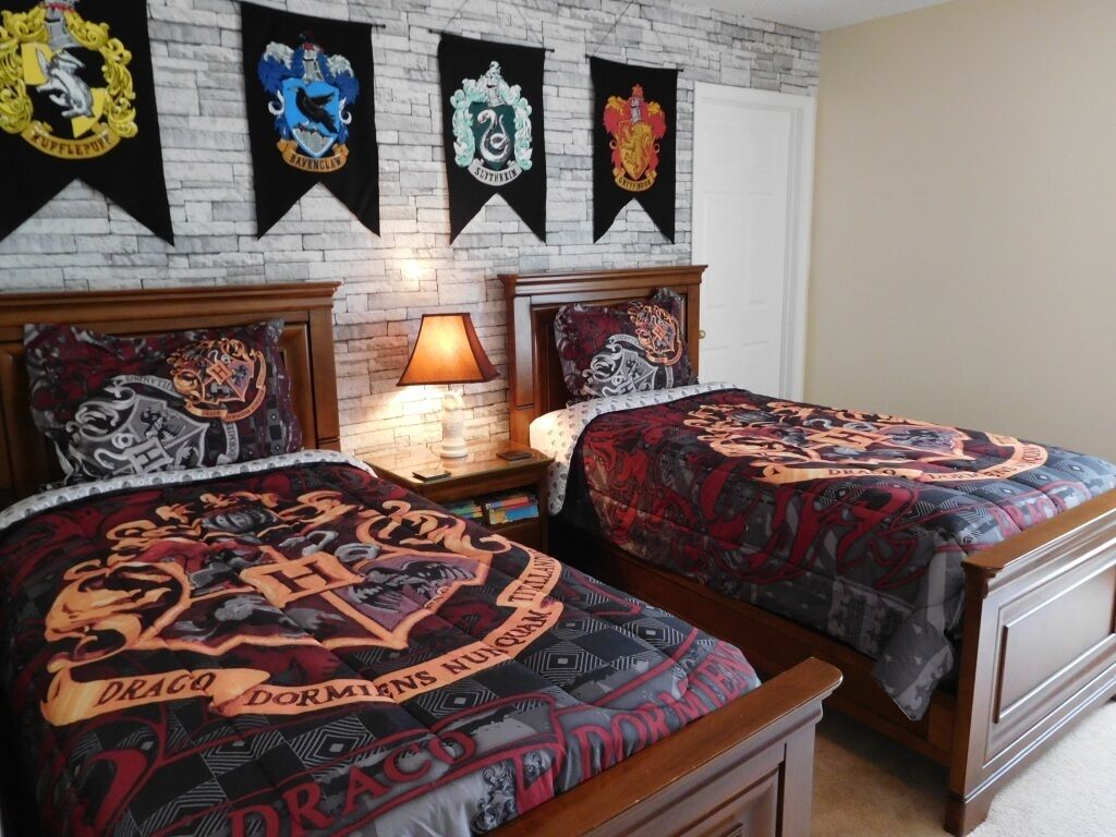 Une chambre avec deux lits, chacun agrémenté d’une housse de couette à motifs, d’une lampe de chevet et d’un mur décoré de quatre bannières.