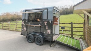 A mobile coffee truck with a small window and a ramp for accessibility.