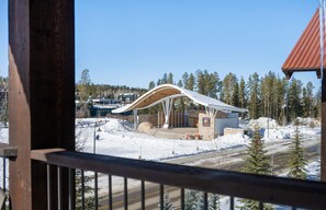 A modern building with a curved roof, surrounded by snow and trees. - NEW! 3BR/3BA Penthouse Downtown, Htd Pool/Hot Tub next to park and playground (winter park)