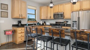 Una cocina moderna con armarios de madera, electrodomésticos de acero inoxidable y taburetes de bar.