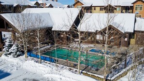 Zona residencial cubierta de nieve con una piscina rodeada por una valla.