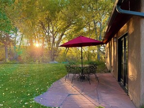 An outdoor patio with a table and chairs, surrounded by a grassy area and trees. - The Vineyard House - A Serene Cottage in the Mountains with Magical Views (Dixon)