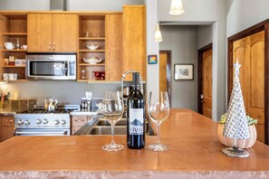 Uma bancada de cozinha com uma garrafa de vinho, dois copos e um enfeite em formato de árvore.