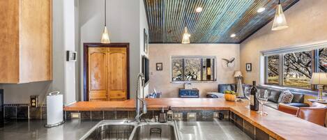 A modern kitchen with a large island, stainless steel appliances, and a rustic ceiling.