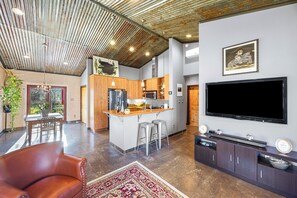 A spacious living area with a large flat-screen TV, a wooden dining table, and a comfortable leather sofa.