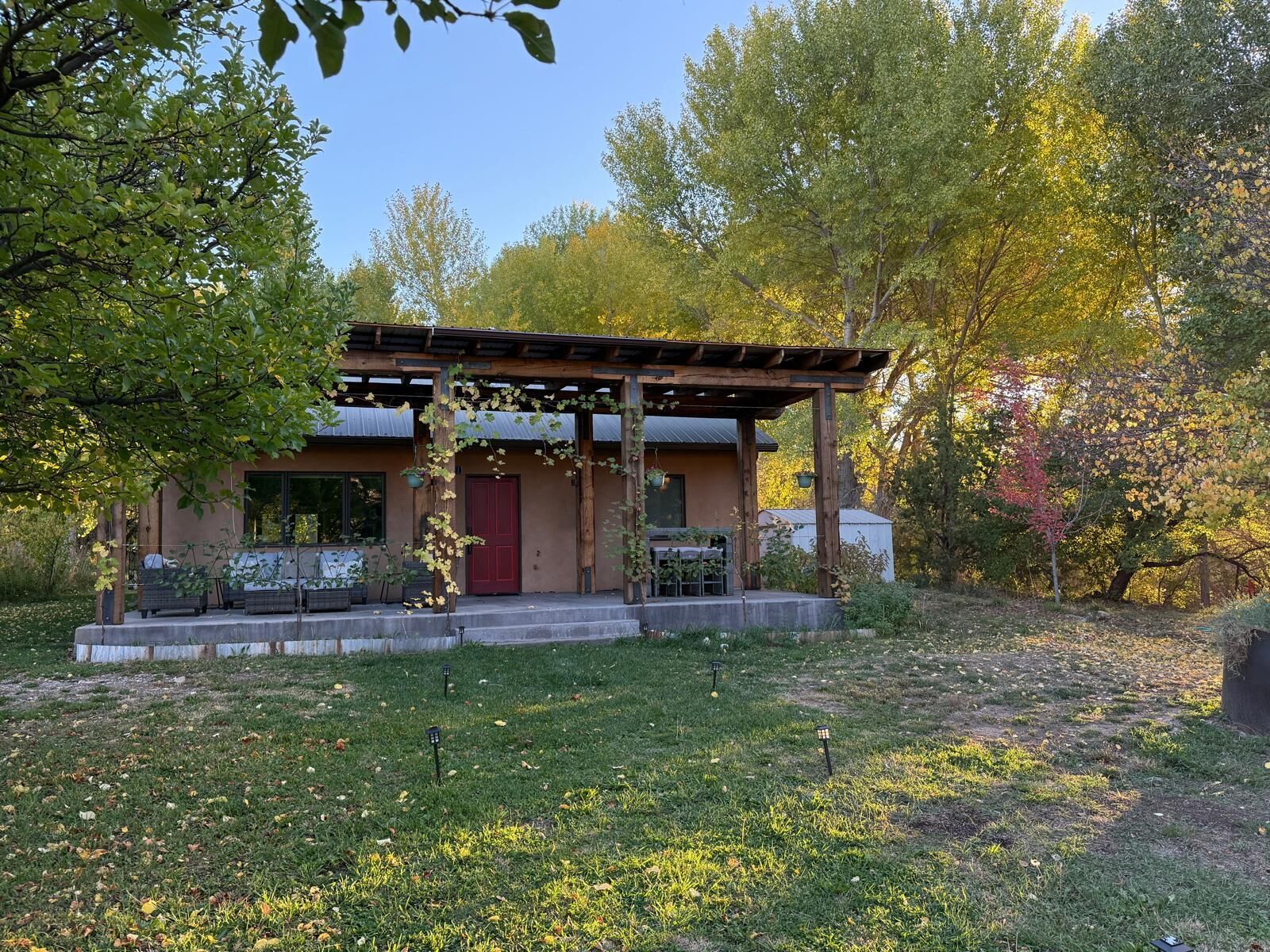 Une maison moderne dotée d’un porche abrité, entourée d’arbres et bordée d’une pelouse.