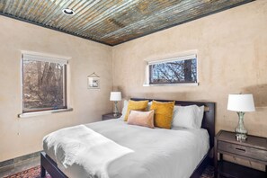 A bedroom with a bed, two bedside tables with lamps, a window, and a ceiling with a light fixture. - The Vineyard House - A Serene Cottage in the Mountains with Magical Views (Dixon)