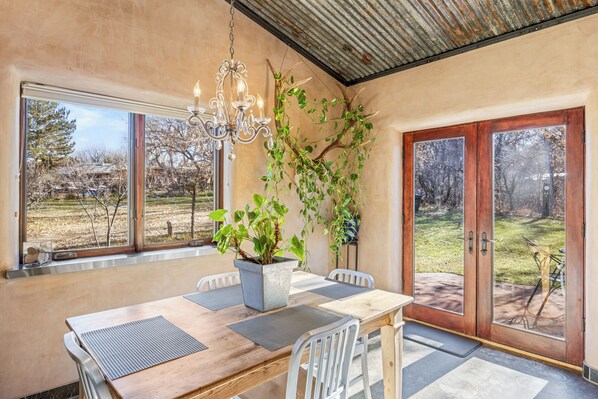 A dining area with a wooden table, chairs, a chandelier, and a potted plant.