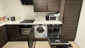 Una cocina compacta con lavavajillas, horno, microondas y lavadora integrada.
