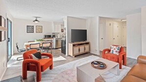 A modern apartment with a dining area, kitchen, living room, and a TV. - Remodeled! Beaverton 2BR/2BA Fenced Backyard Extended Stays (Beaverton)