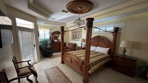 A spacious bedroom with a four-poster bed, a chandelier, and a large window. - Southern Comfort on Hampton Lakes - The Ultimate Luxury Retreat! (Davenport)