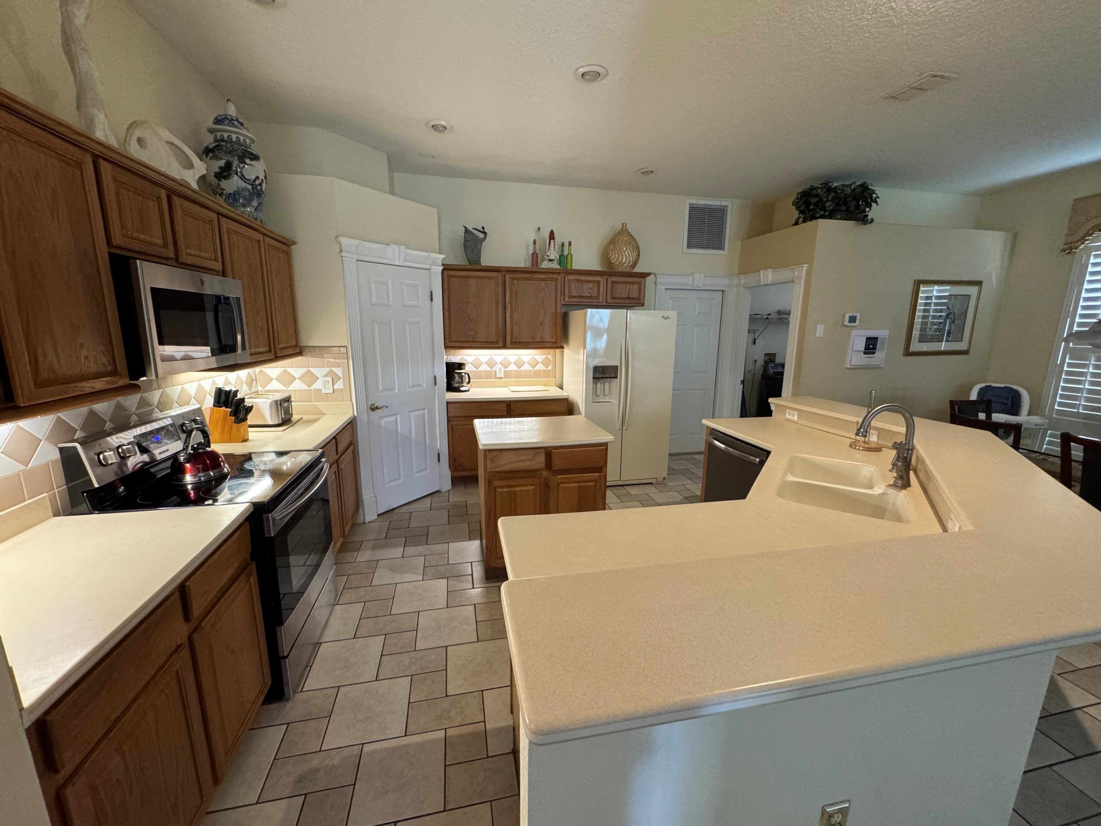 A spacious kitchen with wooden cabinets, a stainless steel stove, a microwave, and a refrigerator.