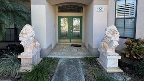 A building entrance with a green door, two lion statues, and a number '409' sign. - Southern Comfort on Hampton Lakes - The Ultimate Luxury Retreat! (Davenport)