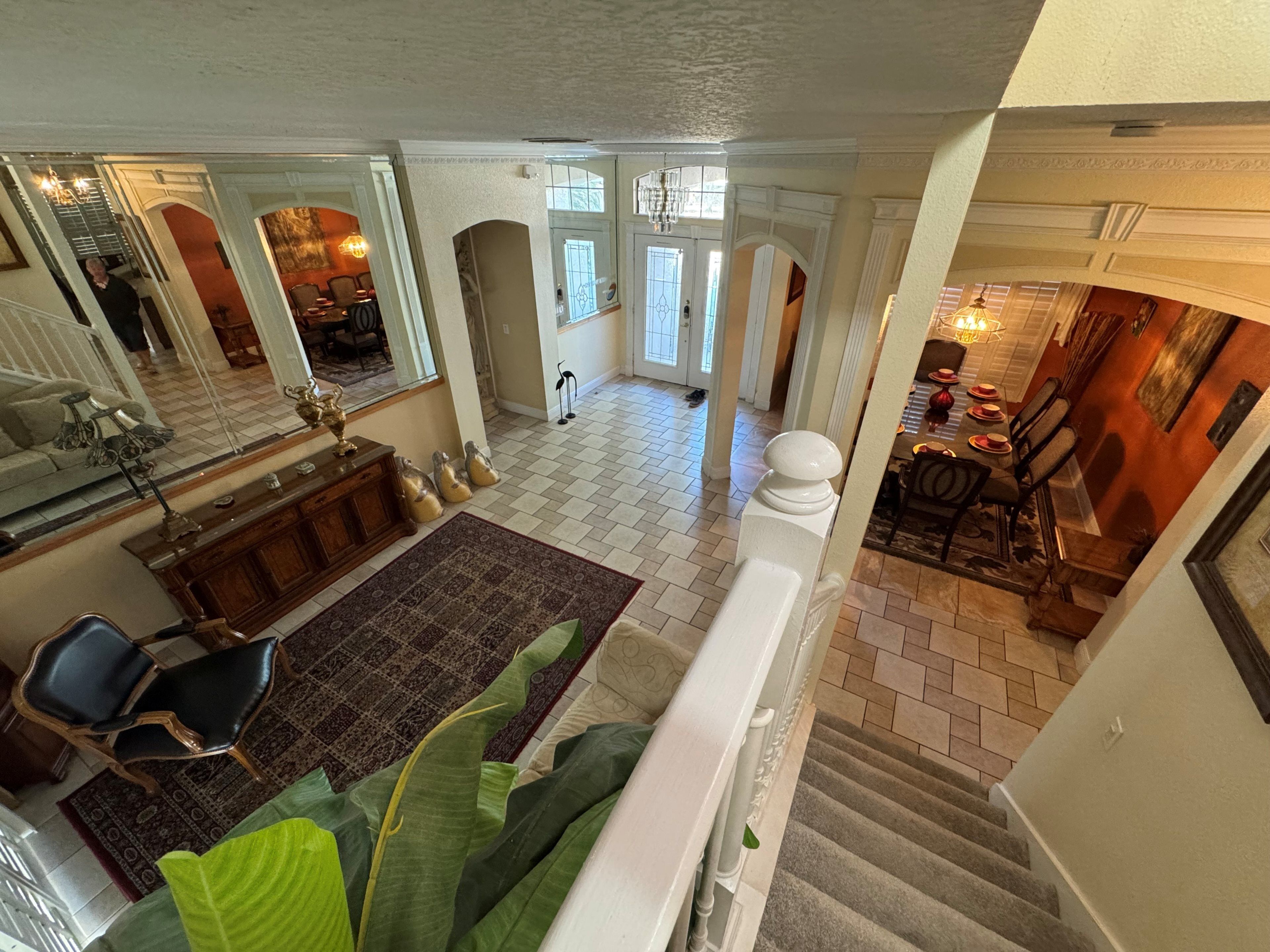 A spacious living area with a large mirror, a dining table with chairs, and a staircase leading to another level.