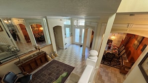 A spacious living area with a large mirror, a dining table with chairs, and a staircase leading to another level. - Southern Comfort on Hampton Lakes - The Ultimate Luxury Retreat! (Davenport)