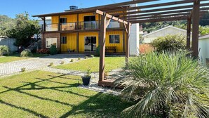 Une maison à deux étages dotée d’un balcon, d’une pergola et d’un jardin bien entretenu.