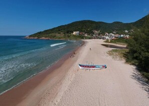 Une plage avec un bateau sur le sable, un ciel dégagé et un paysage vallonné en arrière-plan.