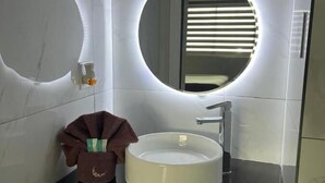 Ein modernes Badezimmer mit einem runden Spiegel, einem Waschbecken und einem Handtuchhalter.