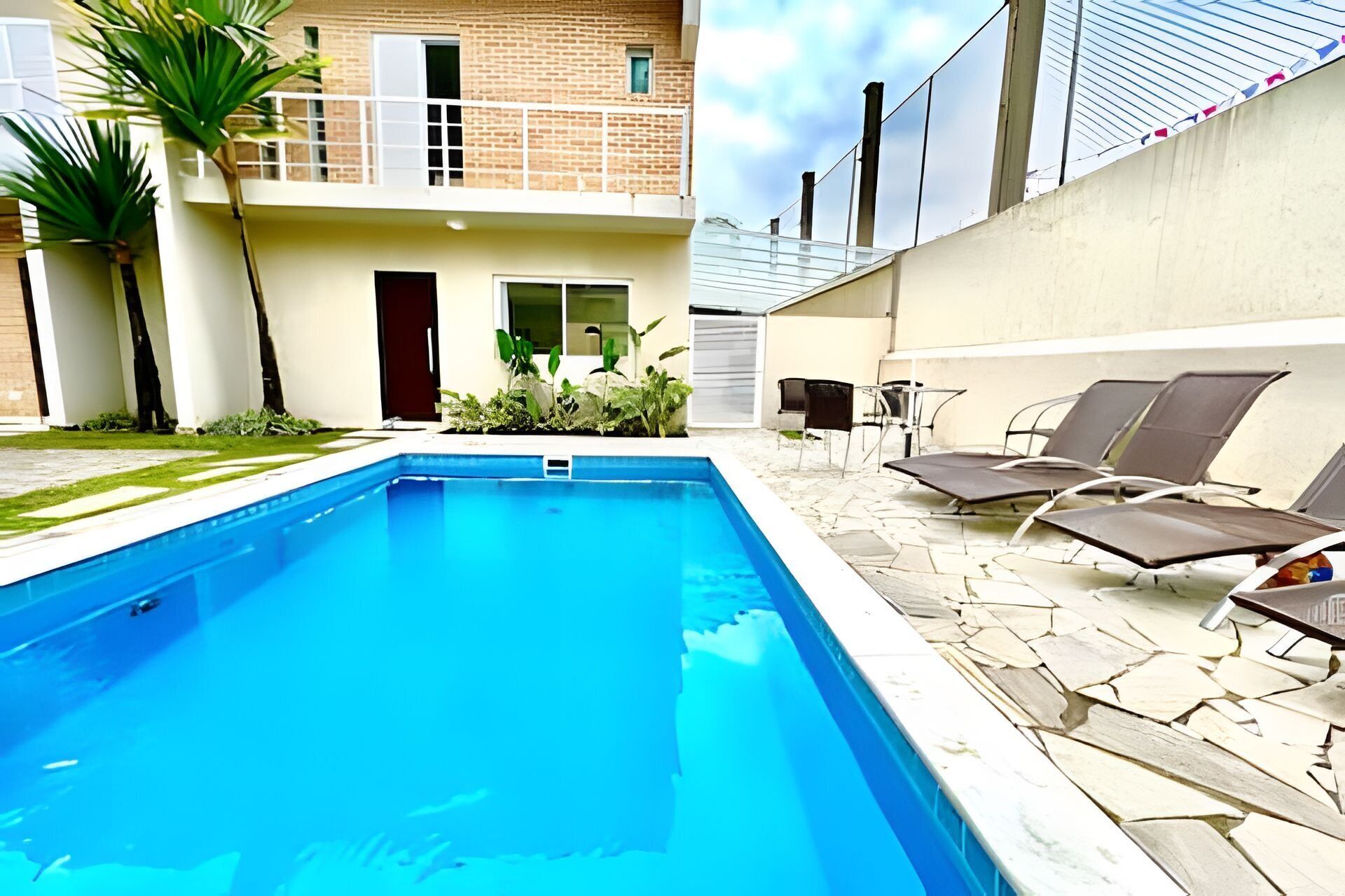 A swimming pool with lounge chairs and a small garden area.