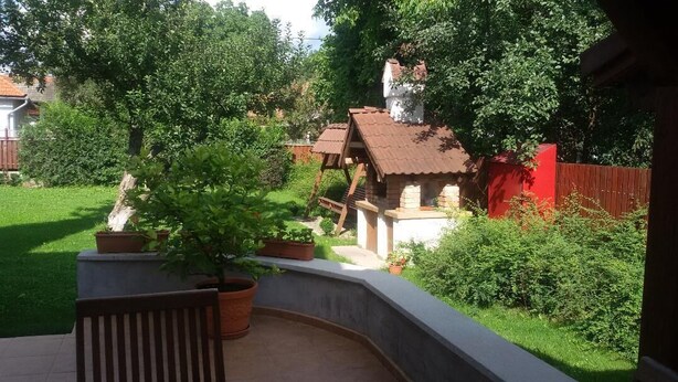 A patio with a wooden chair, a small brick structure, and potted plants. - Casa Dancs (Covasna)