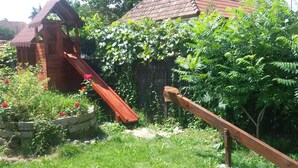 A wooden slide in a garden with a house in the background. - Casa Dancs (Covasna)