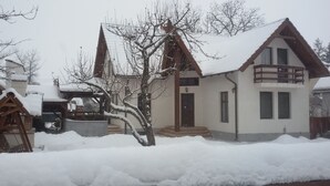 A two-story house with a sloped roof, a balcony on the second floor, and a front door. - Casa Dancs (Covasna)