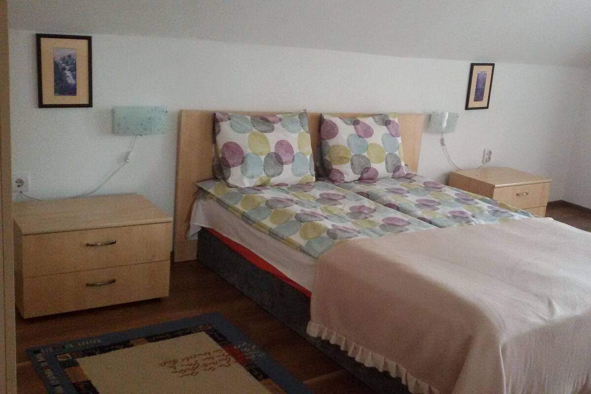 Quarto com uma cama, duas mesas de cabeceira, um criado-mudo, um aparador de madeira e um tapete.
