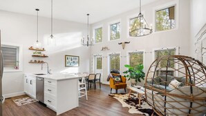 Una cocina amplia con armarios blancos, una isla central e iluminación colgante.