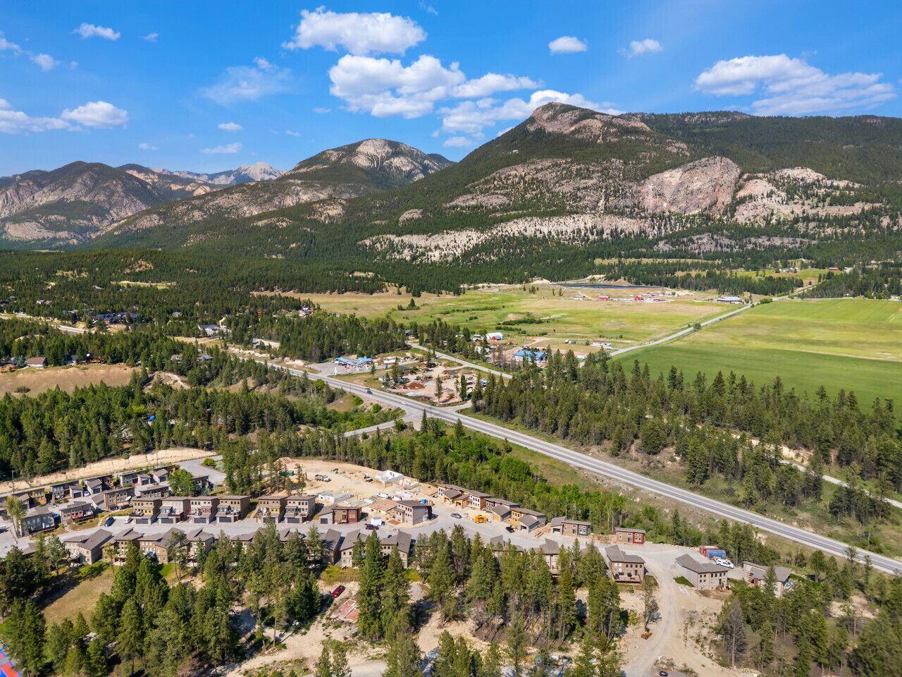 A residential area with houses, a road, and mountains in the background.