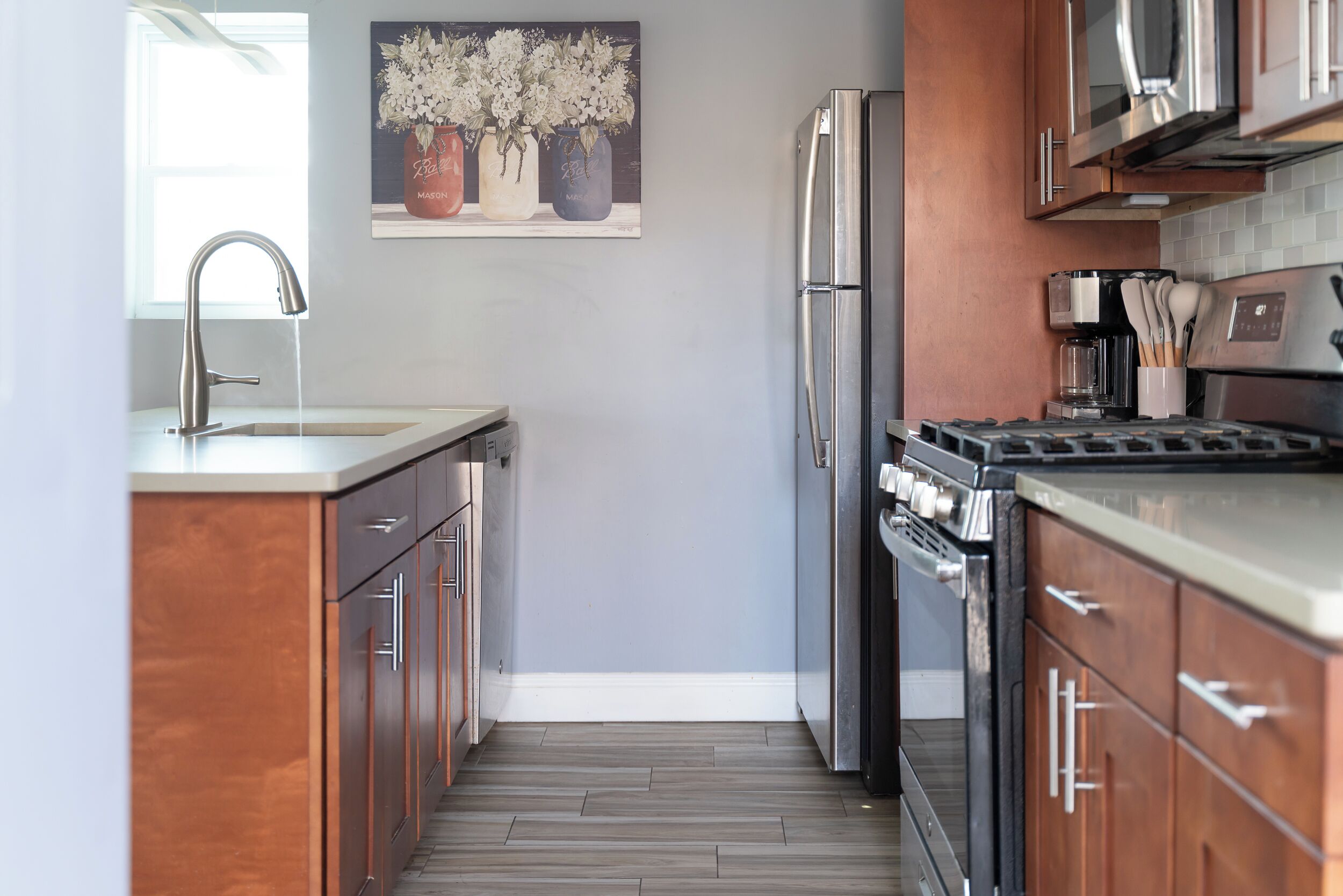 Une cuisine moderne dotée d’appareils électroménagers en acier inoxydable, de meubles en bois et d’un revêtement mural en carreaux.