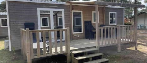 A small wooden cabin with a porch and steps leading to a door.
