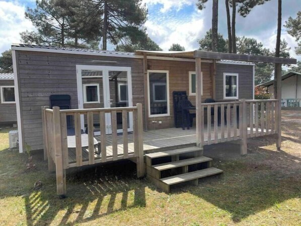 Eine kleine Holzhütte mit einer Veranda und Stufen, die zu einer Tür führen.