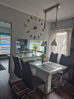 Une cuisine moderne avec un îlot central, des chaises noires et une grande horloge murale.