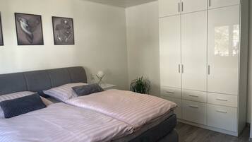 Een slaapkamer met een bed, twee nachtkastjes, een kamerplant en een kledingkast.