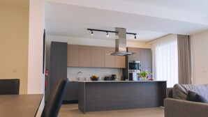 Una cocina moderna con una isla central, electrodomésticos integrados y un comedor con mesa y sillas.